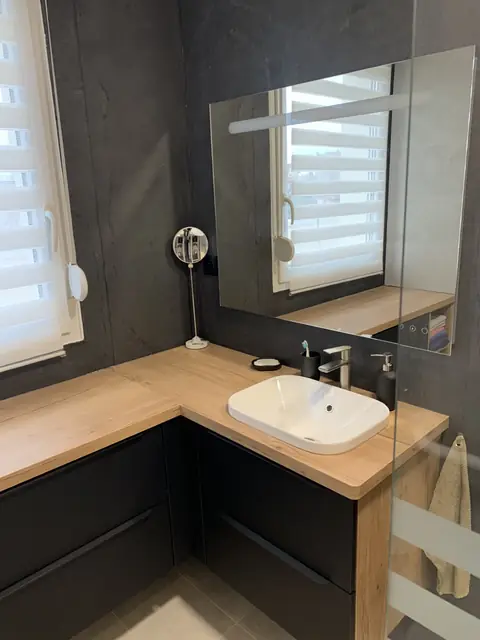 Salle de bain sur mesure à Saint-Max : plan vasque en chêne, meubles noirs, mur sombre